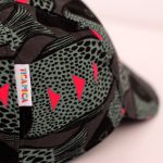 Gorra con visera y cierre con velcro. Estampado en negro y gris y detalles en fucsia