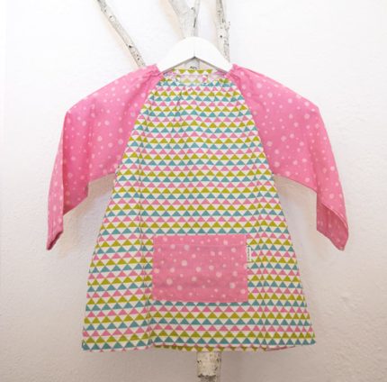 Bata para guardería, con estampado de triángulos y mangas y bolsillo delantero en rosa.