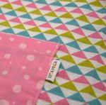 Bata para guardería, con estampado de triángulos y mangas y bolsillo delantero en rosa.