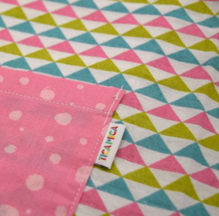 Bata para guardería, con estampado de triángulos y mangas y bolsillo delantero en rosa.