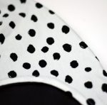 Gorro infantil de invierno con estampado de lunares en negro sobre blanco.