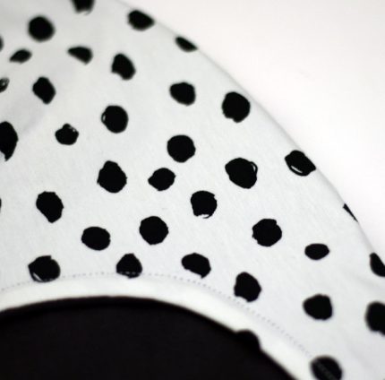 Gorro infantil de invierno con estampado de lunares en negro sobre blanco.